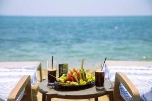 ElaiokhórionAnasa Luxury Resort的海滩上的一张桌子,上面放着一碗水果和饮料