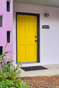 富丽海滩Folly Vacation Great Location, Vintage and Fun 120 Unit A的紫色和白色房子上的黄色门