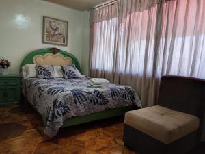 伊瓦拉Hotel Altamira Suites - Ibarra的一间卧室配有绿色的床和椅子