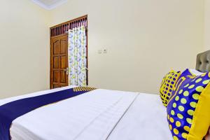 普兰巴南SPOT ON 93007 Guest House Lestari的一间卧室配有一张床和一扇木门
