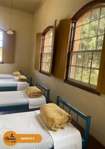 欧鲁普雷图Brumas Ouro Preto Hostel e Pousada的窗户房间里一排床