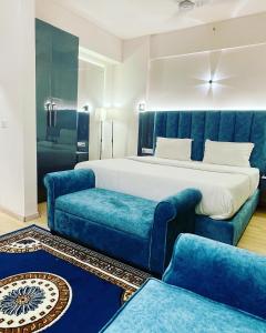 勒克瑙Neel Skye - Couple Friendly - DLF My Pad, Gomtinagar , Lucknow的一间卧室配有一张床和两张蓝色椅子