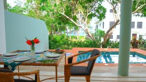 迪亚尼海滩The Pool House & The Colobus House, Bella Seaview, Diani Beach, Kenya的池畔露台配有桌椅