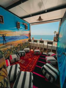 塔哈佐特Sunrise Hostel Taghazout的一间配备有椅子的房间和海滩绘画