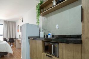 波苏斯-迪卡尔达斯Maravilhoso e elegante studio para casal PGO412的厨房配有微波炉和冰箱。