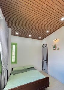 大叻HaHe Homestay的一间卧室设有一张床和木制天花板