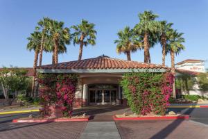 兰乔米拉日棕榈泉/牧场米拉吉希尔顿花园旅馆的一座拥有粉红色花卉和棕榈树的建筑