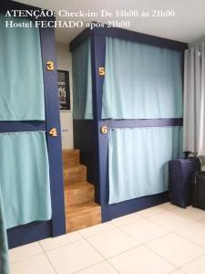 巴西利亚Elô Hostel的一间设有蓝色窗帘的客房和楼梯间