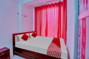 巴特那OYO Flagship Hotel Celebrate Inn的一间卧室配有一张带红色窗帘的床