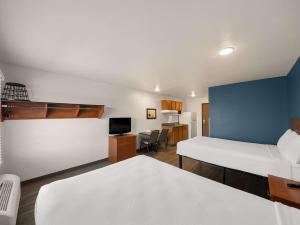 罗克沃尔WoodSpring Suites Dallas Rockwall的客房设有一张床、一张书桌和电视