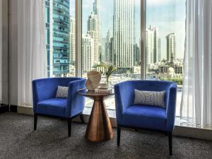 迪拜Pullman Dubai Downtown的配有大窗户的客房内配有两把椅子和一张桌子