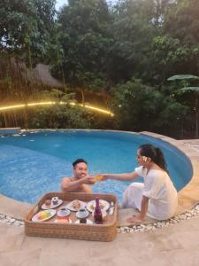 外南梦The Osing Bamboo Resort - a LIBERTA Collection的坐在游泳池里的男人和女人