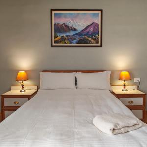 加德满都Boudha Apart Hotel的一间卧室配有一张带两盏灯的大型白色床。