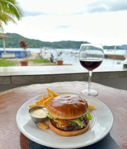科隆Panama Dive Adventure的汉堡包、薯条和一杯葡萄酒的盘子