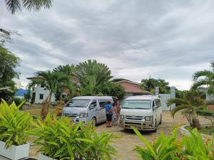 公主港Cheryl's Place Vacation Home Palawan的两个人站在两辆货车旁边,停在一个院子