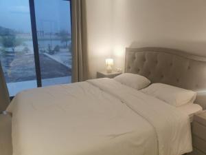 Wādī KhasbarHawana VIP Private Apartment的卧室配有白色的床和大窗户