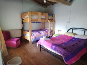 塔尔马Casa de Campo-Hospedaje Munay Wasi的一间卧室配有两张双层床和椅子