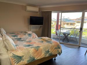 阿勒达拉乌拉杜拉港汽车旅馆 的一间卧室设有一张床,阳台配有电视。