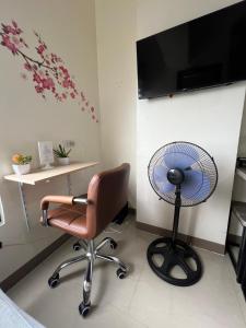 宿务Cozy Studio, super fast internet, workspace and washer的客房配有书桌、风扇和椅子。