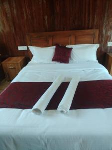玛莱尤尔Don's River Valley Jungle Resort的一张配有白色床单和红色枕头的大床