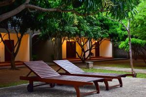 锡吉里亚Tropicara Resort的两张野餐桌,坐在一座树木繁茂的建筑旁边