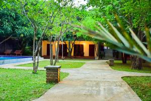 锡吉里亚Tropicara Resort的公园里一条有建筑和树木的走道