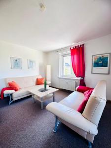 约翰乔治城Ferienwohnung Johanngeorgenstadt的客厅配有2张白色沙发和红色窗帘