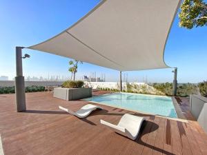 迪拜StoneTree - Anwa By Omniyat 2BR - Luxury Apartment的一个带两把白色椅子的庭院和一个游泳池