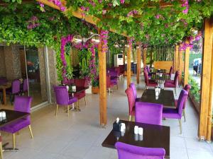 贝利克杜祖Gardan Hotel的餐厅设有紫色椅子、桌子和鲜花