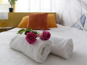 朴次茅斯Open Mind Property - Luxury Apartment in the City的一张带毛巾的床和两朵玫瑰花