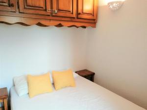 莫里永Appartement Morillon 1100, 3 pièces, 6 personnes - FR-1-412-17的卧室配有白色床和2个黄色枕头