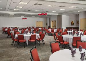 安娜堡安娜堡希尔顿花园酒店的宴会厅配有白色桌子和红色椅子