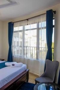 尼亚利Lux Suites Impala Apartments Nyali的一间卧室配有一张床和一个带椅子的窗户