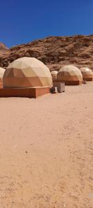 亚喀巴Wadi Rum Marcanã camp的沙漠中的三座圆顶建筑群