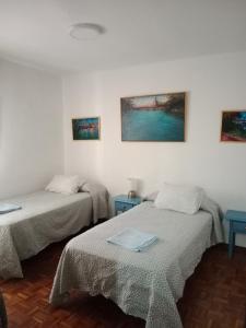 塞维利亚Apartamento zona Palacio de las Dueñas y las Setas的一间设有两张床和两张蓝色桌子的房间