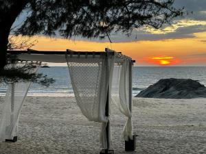 乌杜皮The Postcard on the Arabian Sea的海滩上的一张床铺,背靠日落