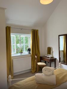 亨利昂泰晤士Mews house in the centre of Henley-on-Thames的一间卧室配有一张床、一张书桌和一个窗户。