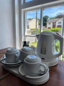 LlangristiolusHolland arms hotel的茶壶和茶杯放在桌子上的托盘上