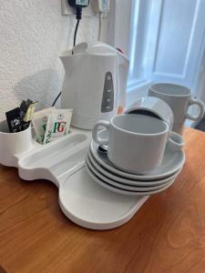 LlangristiolusHolland arms hotel的一张桌子,上面放有盘子和杯子,还有咖啡壶