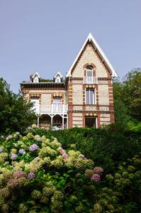 埃特勒塔Villa Eliane - parking privé的一座大砖房,位于一座鲜花盛开的山顶上