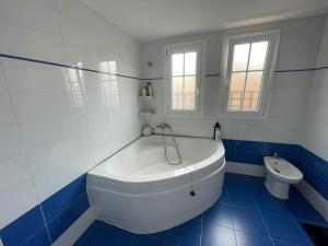 阿尔么丽亚Tokyo Rooms (El Playazo) - Habitación PREMIUM con baño privado的蓝色和白色的浴室设有浴缸和卫生间