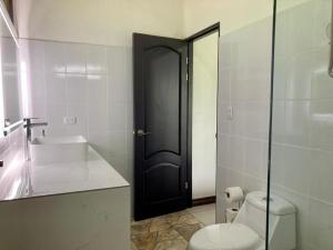 San PedrilloEden Corcovado的一间带卫生间、水槽和黑色门的浴室