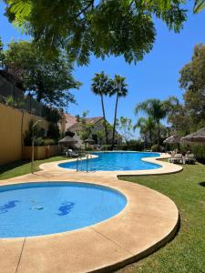 贝纳尔马德纳Townhouse beachfront Benalmadena-Costa的一座大游泳池,位于一个树木繁茂的庭院内