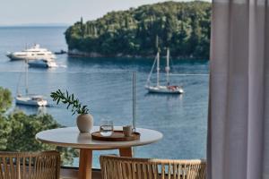 卡拉米San Antonio Corfu Resort (Adults Only)的一张桌子,上面放着一杯葡萄酒和两把椅子