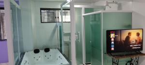 卢米亚Pousada Hotel Lumiar的带浴缸的浴室和电视。