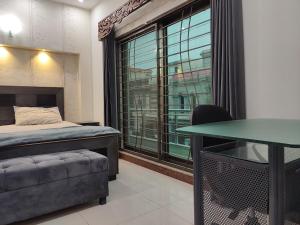 拉合尔Fully Serviced Holiday Home Near Lahore Ring Road的一间卧室配有一张床、一张桌子和一个窗户。