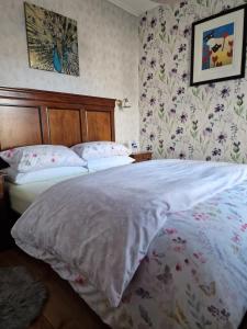 布莱尔高里Isla Rose Cottage的一间卧室配有一张带白色床单和花卉壁纸的床