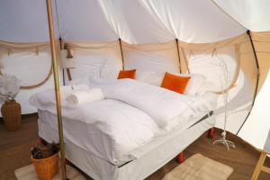 Shāhiq游猎沙漠营地度假酒店的帐篷内的一张床位,配有白色床单和橙色枕头