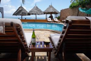 马特姆维Zanzibar House Boutique Hotel的游泳池畔的桌子上放一瓶葡萄酒