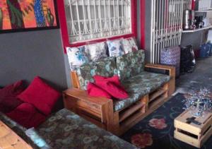 马塞约"LE CHAT QUI PECHE" Hostel a 150 metros da PRAIA de PAJUCARA的带沙发和红色枕头的客厅